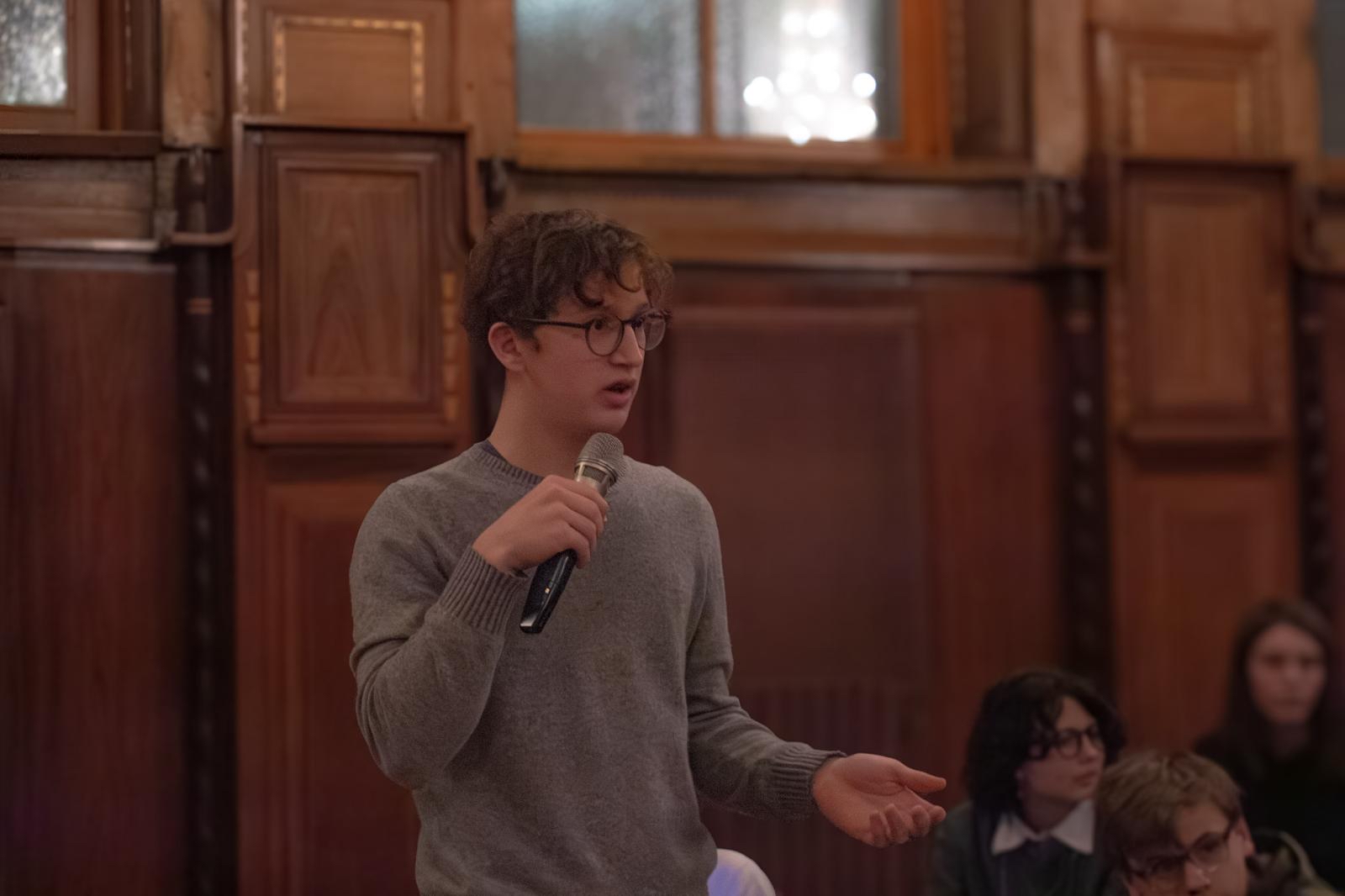 Maximilian Havas speaking into a microphone at a leadership event